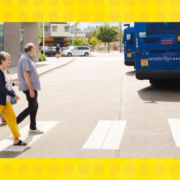People walking across the street behind buses