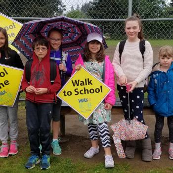 Kids and teacher at school holding Walk N Roll signs