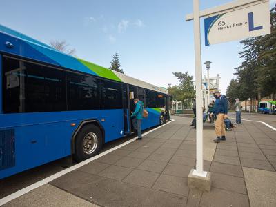 Intercity Transit bus with passengers waiting at a bus stop