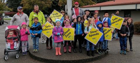 Image of kids and adults at school holding signs